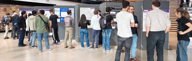 People reading research posters at the Google DeepMind Research Ready Summer Internships 2025 poster session in a large indoor space.